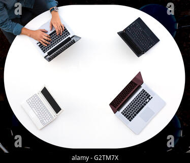 Vue de dessus de bureau arrondi avec quatre ordinateurs portables Banque D'Images