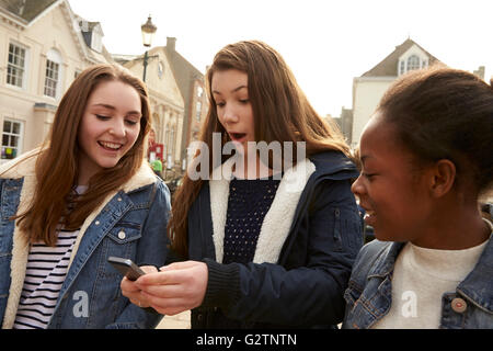 Les jeunes filles à marcher le long de la rue à la recherche de médias sociaux Banque D'Images