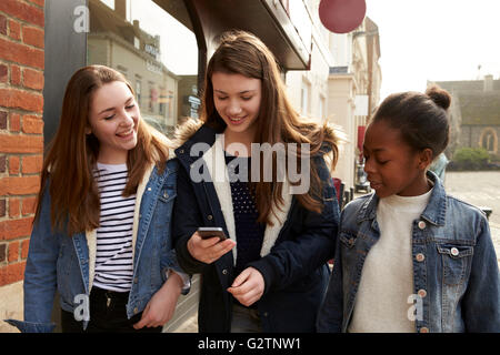 Les jeunes filles à marcher le long de la rue à la recherche de médias sociaux Banque D'Images