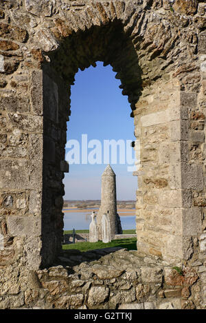 L'Irlande, dans le comté d'Offaly, Clonmacnoise, Temple Finghin et McCarthy's Tower vue à travers une fenêtre ouverte de la cathédrale. Banque D'Images