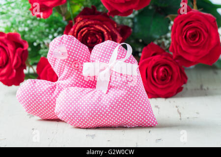 Coeurs roses avec des roses rouges sur une table en bois. Banque D'Images