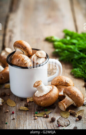 Champignons Champignons dans la tasse et épices sur table en bois. Banque D'Images