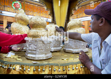 Les gens l'ajout de feuilles d'or à cinq images du bouddha doré à l'intérieur de la pagode phaung daw oo au lac Inle, à l'État de Shan, myanmar Banque D'Images