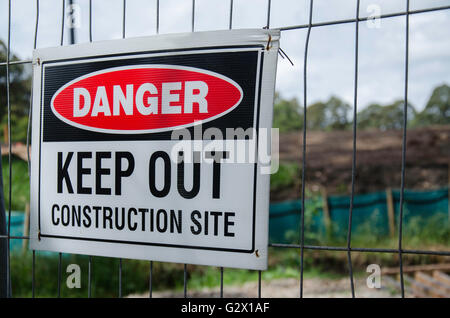 Un point de rassemblement d'urgence signe épinglé à clôtures temporaires en face de l'échafaudage en alliage sur un site de travail de construction en Australie Banque D'Images