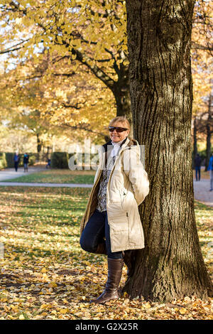 Mûres, smiling woman in autumn park à tree, vertical Banque D'Images