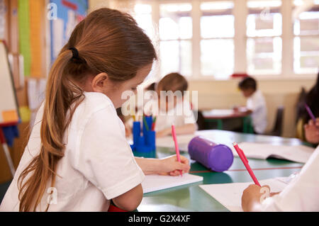 Les élèves qui travaillent à un bureau dans la salle de classe de l'école élémentaire Banque D'Images