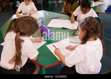 Les élèves qui travaillent à un bureau dans la salle de classe de l'école élémentaire Banque D'Images