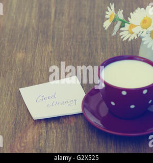 Fleurs Daisy et tasse de lait avec un bon matin note sur fond de bois bleu rustique Banque D'Images