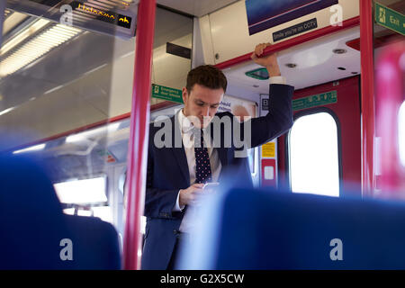 Businessman Reading Text Message On Train durant la navette Banque D'Images