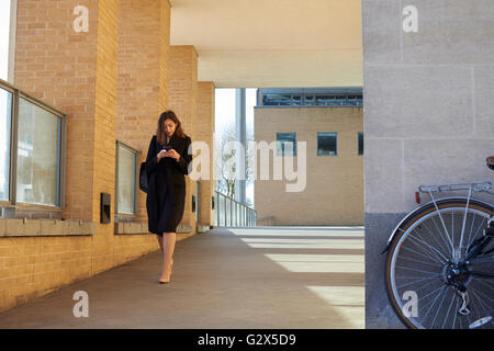 Businesswoman lit les messages texte sur chemin du travail Banque D'Images