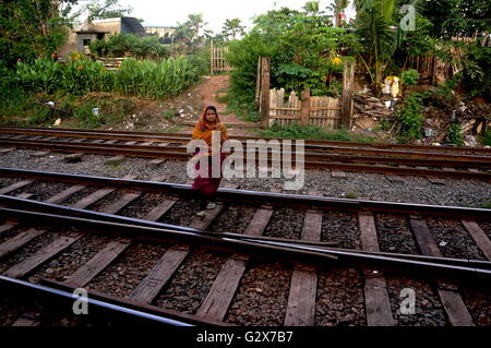 Une femme portant un sari promenades sur les voies ferrées dans une banlieue nord de Colombo, Sri Lanka. Banque D'Images