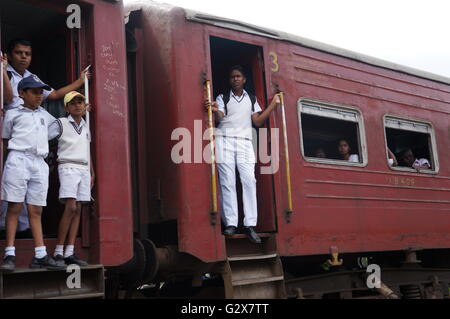 De jeunes étudiants en uniforme sur le chemin du retour de l'école comité permanent sur les plates-formes d'un vieux train, Kandy, Sri Lanka. Banque D'Images
