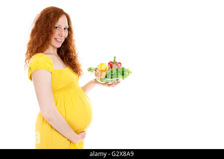 Pregnant woman holding un bol de légumes et de sourire. Isolé sur blanc. Banque D'Images