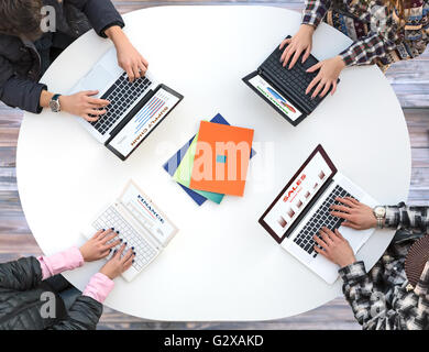 Vue de dessus de bureau arrondi blanc avec quatre ordinateurs portables et mains Les gens de taper au clavier Banque D'Images