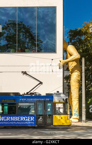 Sculpture d'homme géant avec la tête coincée dans le mur, Berlin , avec un tram passant par Berlin Banque D'Images