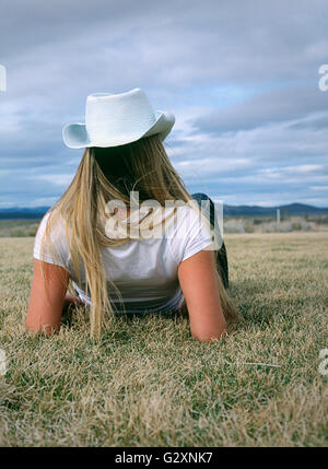 Une femme portant un chapeau blanc assis dans les champs. Banque D'Images