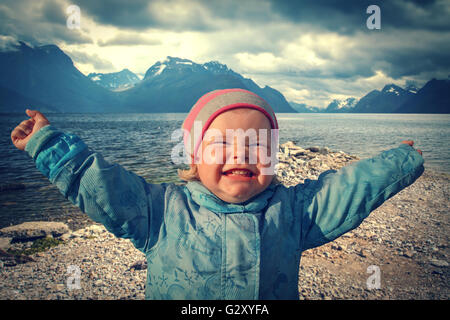 Girl queen of the north. Une jeune fille se tient sur les rives du fjord, bras tendus sur les côtés de la joie. Banque D'Images