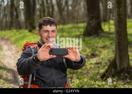 L'homme en photo sur backpacker son appareil photo dans la forêt Banque D'Images