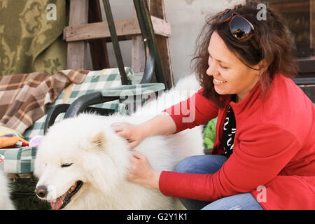 Happy young woman with white fluffy Samoyède chien, portrait en extérieur Banque D'Images