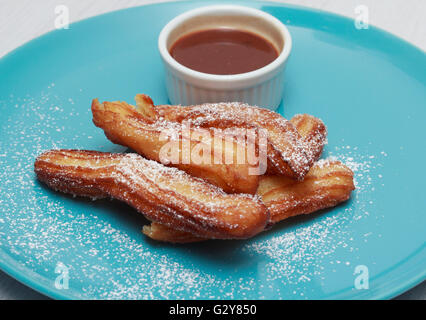 Churros sur plaque bleue avec une sauce au chocolat Banque D'Images