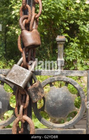 Vieux serrure rouillée sur une barrière métallique dans le jardin. Serrure sur la porte de fer. L'emprisonnement de symbole et d'esclavage. La chaîne de sécurité de la propriété. Banque D'Images