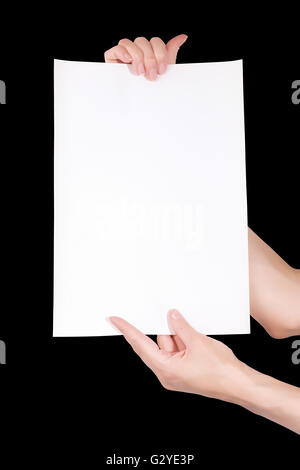 Femme mains tenant la feuille de papier vierge vertical isolé sur black with clipping path Banque D'Images