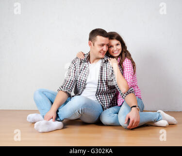 Portrait Of Happy Young Couple Sitting on Floor Looking up prêt pour votre texte ou d'un produit Banque D'Images