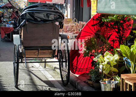 Scène de rue en Thaïlande Chinatown avec vintage rickshaw et parapluie rouge Banque D'Images