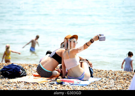 Deux personnes parlent une des selfies la foule sur la plage de Brighton, Sussex. Banque D'Images