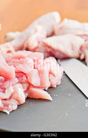 Couper les morceaux de poulet non cuit sur une planche à découper en plastique Banque D'Images