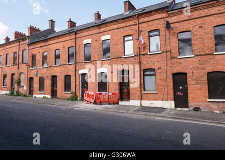 Une longue rangée de maisons abandonnées dans une rue barricadés avec des plaques d'acier. Banque D'Images