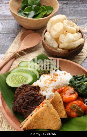 Nasi Padang Padang plat de riz ou, à l'Ouest de Sumatra, magnifiquement arrangé sur plaque de bois ; servi avec des chips de peau de vache. Banque D'Images