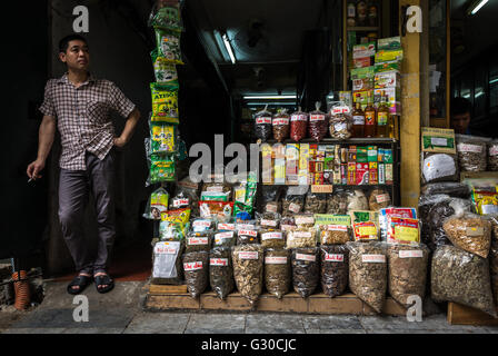 Un vendeur d'épices en prenant une pause-cigarette dans la vieille ville de Hanoi, Vietnam. Banque D'Images