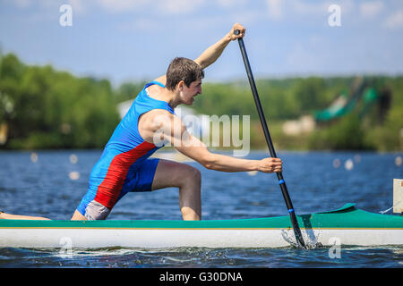 Gros plan du canoéiste athlète rowing avec une rame dans un canot au cours du championnat de l'Oural à l'aviron Banque D'Images