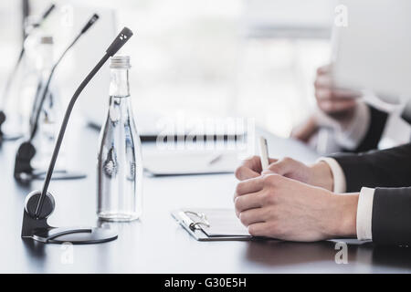 Des micros sur le tableau dans la salle de conférence et homme d'affaires, mains Banque D'Images