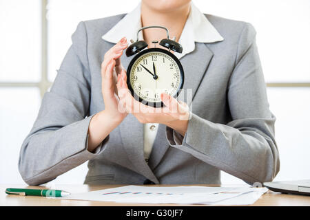 Business Woman holding clock in office Banque D'Images