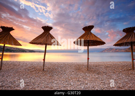 Des parasols de paille sur la plage de Baska, sur île de Krk Banque D'Images