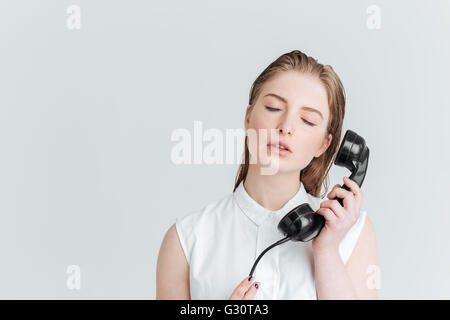 Relaxed woman with closed eyes holding retro phone tube isolé sur fond blanc Banque D'Images