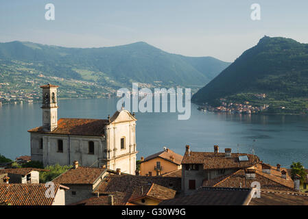 Église de San Rocco dans Marone village avec panorama sur le lac d'Iseo et Monte Isola île dans la lumière du soir, Lombardie, Italie Banque D'Images