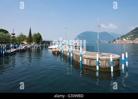 Poteaux colorés au port d'Iseo sur le lac d'Iseo avec le panorama de Monte Isola et la côte rocheuse, Lombardie, Italie Banque D'Images