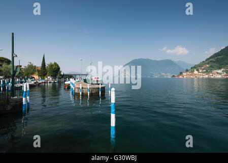 Poteaux colorés au port d'Iseo sur le lac d'Iseo avec le panorama de Monte Isola et la côte rocheuse, Lombardie, Italie Banque D'Images
