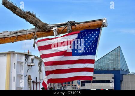 Baltimore, USA - un drapeau américain est suspendu au mât d'un navire avec l'Aquarium National dans l'arrière-plan Banque D'Images