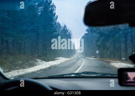 Vue du pare-brise. La conduite d'une voiture sur la route d'hiver dans la région de blizzard Banque D'Images