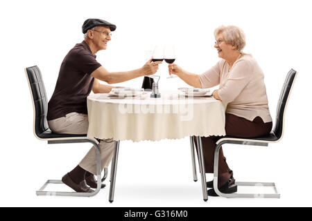 Couple de personnes âgées faisant un toast avec du vin rouge assis sur un rendez-vous romantique isolé sur fond blanc Banque D'Images