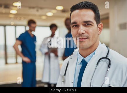 Médecin homme avec des collègues en arrière-plan, médecin à l'équipe d'urgence à l'appareil photo avec en arrière-plan Banque D'Images