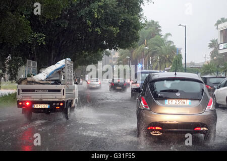 Aci Trezza, Italie, les voitures roulent sur une rue inondée par l'eau de pluie Banque D'Images