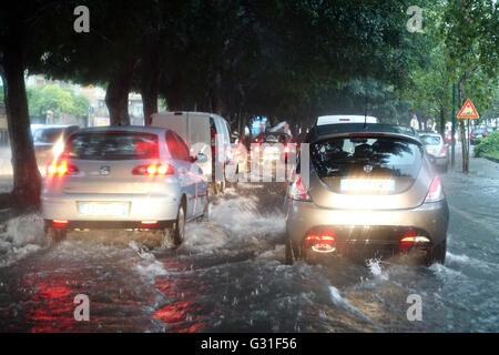 Aci Trezza, Italie, les voitures roulent sur une rue inondée par l'eau de pluie Banque D'Images