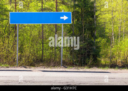 Panneau routier bleu près de l'autoroute avec place pour le nom de la destination et blanc Flèche de direction Banque D'Images