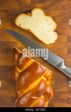 Gros morceaux de pain tressé avec couteau sur fond de bois Banque D'Images