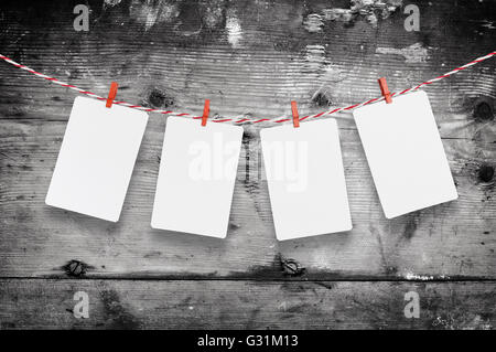 Le papier blanc ou Cadres à photo accroché sur le fil à linge rayé rouge . Fond de bois. Modèle pour votre texte. Banque D'Images